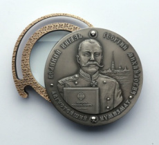 Георгий Романов на инновационном жетоне с лупой в честь 299-летия основания СПМД и Дня монетчика